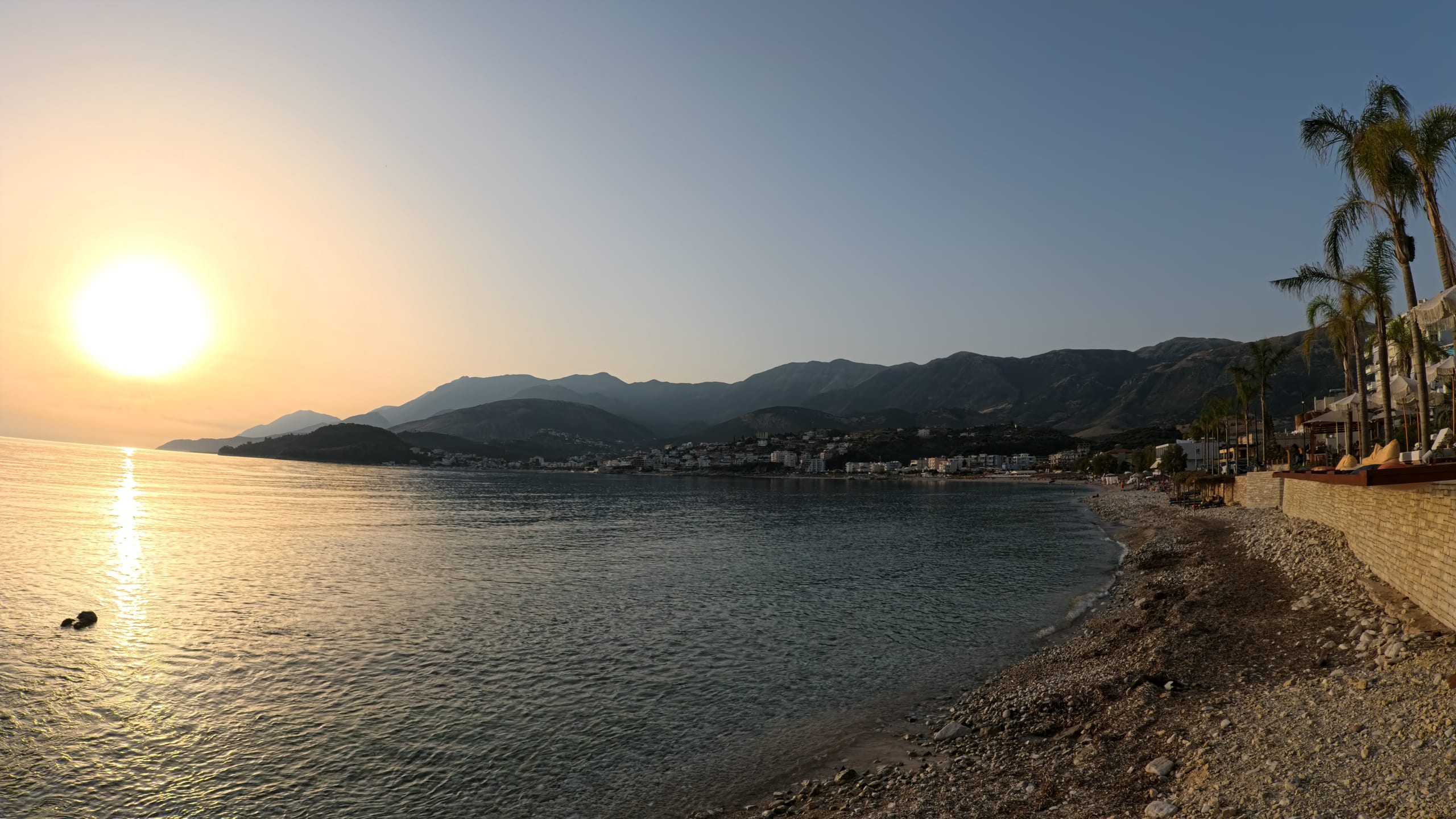 The sun setting over Potami beach and the bay of Himarë, with the Ceraunian mountains behind