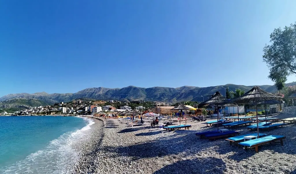 Sunbeds and thatched umbrellas on the pebbles of Potami beach, Himarë