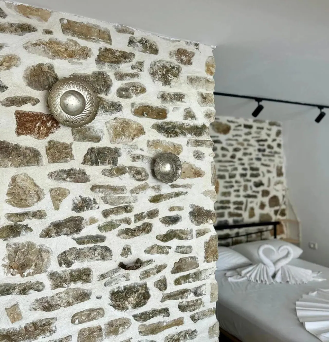 An iron bed and a round mirror against the original stone wall of the old house